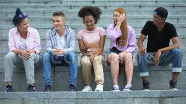 多民族青年群体坐在学院楼梯上，闲暇时间
